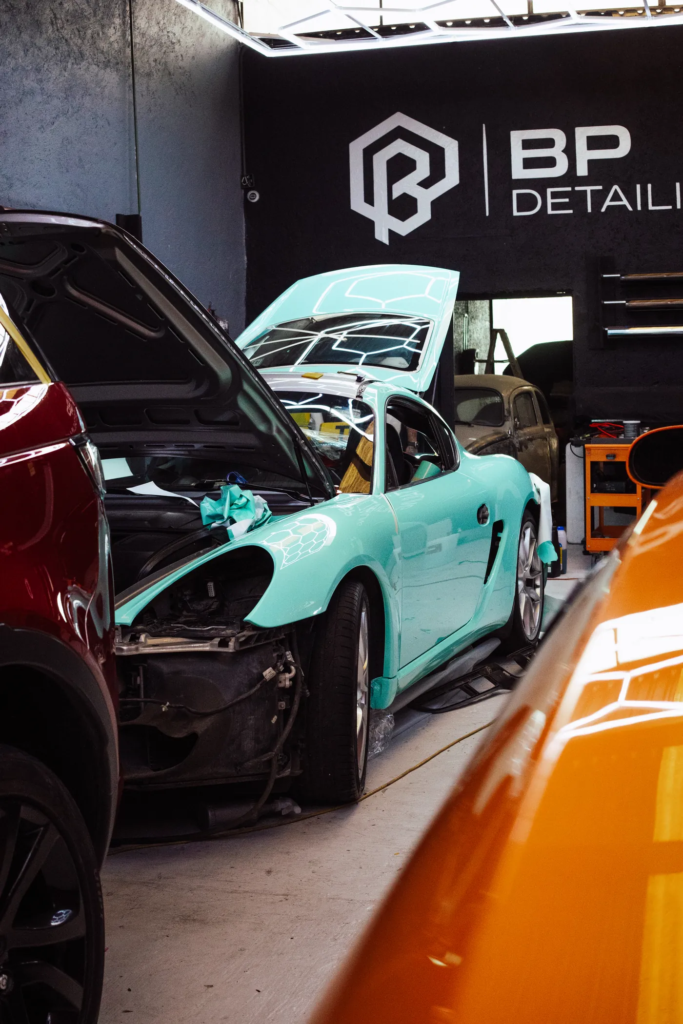 Automóviles y logo de BP Detailing bajo el techo de luces hexagonales